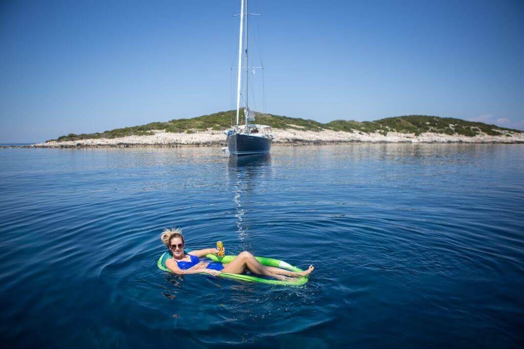 woman lying on a swimming bed in front of a yacht